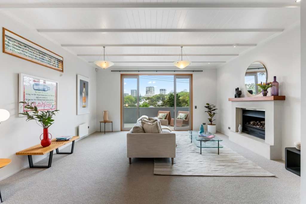 Bright, luxury living room with fireplace opening onto a balcony in an Auckland home